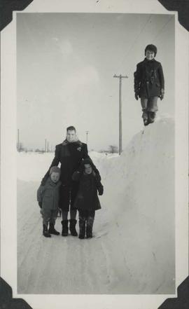 Lady with two children and boy standing on a high snow bank