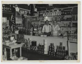 A woman and man shown behind the sales counter inside of Mooney's Store, Ivy Lea