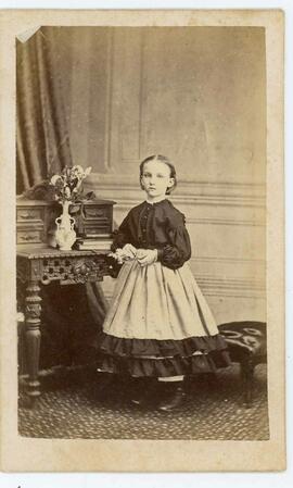 Portrait of small girl standing at table - Photographer A.C. McIntyre, Brockville, Ont