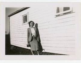 Woman with camera standing beside a house, inscribed “Mary Louise”.