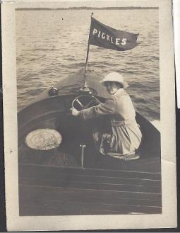 Woman driving boat , flag on boat says Pickles